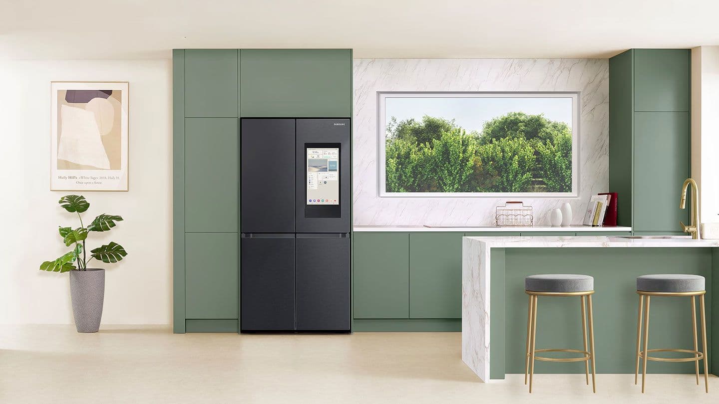 Moderne Küche mit grünen Schränken, schwarzem Kühlschrank, Fenster mit Blick auf Pflanzen und minimalistischen Barhockern.