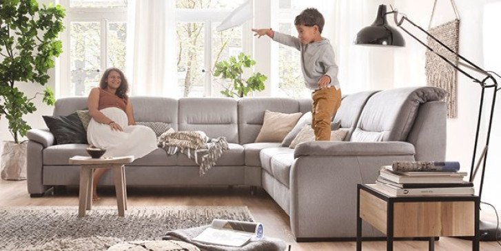 Wohnzimmer mit grauer Couch und fröhlicher Familie